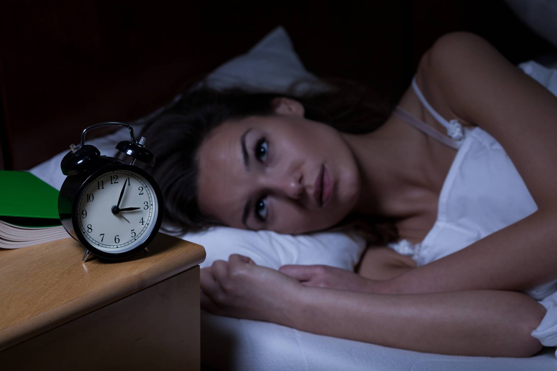 Kvinde der ikke kan sove med et vækkeur ved sin side